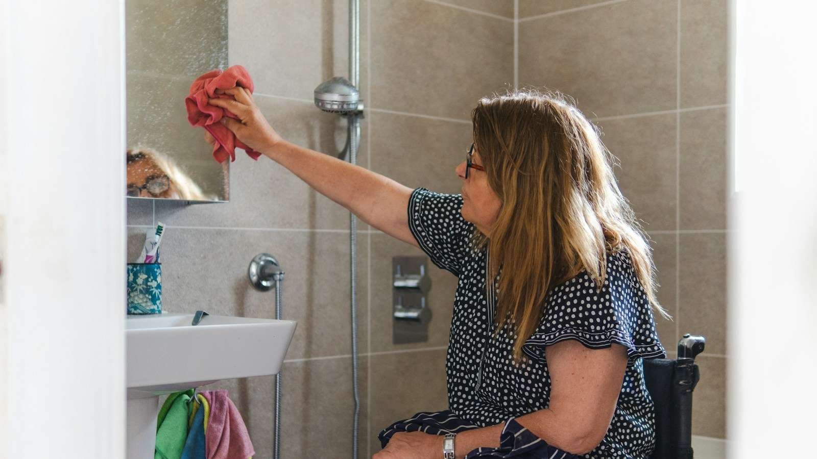 Petugas rumah tangga membersihkan dinding kamar mandi dari bagian atas menuju lantai