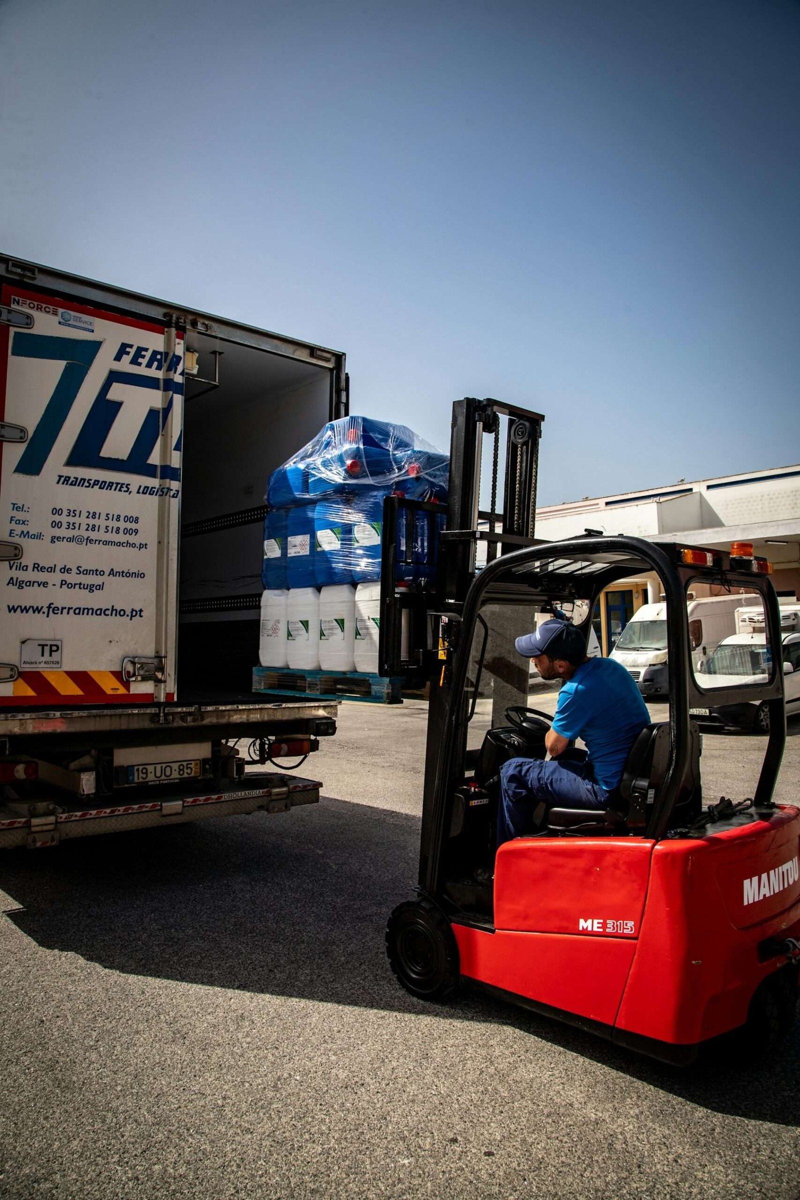 Forklift mengangkat barang di atas palet menuju truk pengiriman